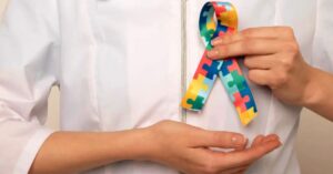 Nova lei diagnóstico autismo p- Profissional de saúde segurando fita colorida com padrão de peças de quebra-cabeça, símbolo associado ao autismo.