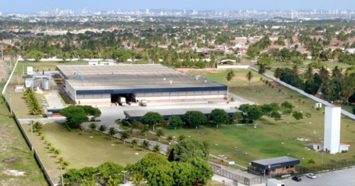 Vista aérea da unidade industrial da Santana Textiles, cercada por área verde e integrada ao ambiente local.