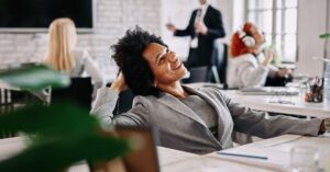 Profissional sorridente em ambiente de trabalho representando o bem-estar corporativo.