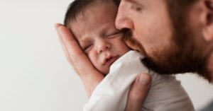 lei da licença-paternidade - Pai beijando o bebê nos primeiros dias de vida