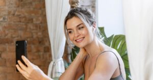 mulher tirando selfie em casa enquanto reflete sobre a neurociência dos padrões de beleza