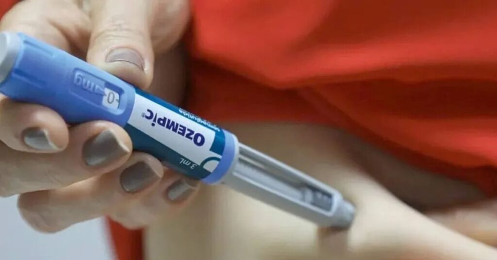 Pessoa aplicando medicamento enquanto o foco destaca caneta injetável de Ozempic, ilustrando o avanço do Orforglipron versão do Ozempic como alternativa oral.