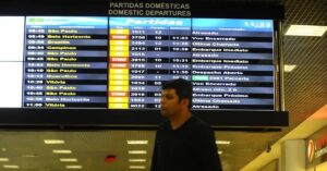 Painel de partidas em aeroporto brasileiro mostra voos atrasados, cenário comum nos Feriados de 2026 com maior fluxo de viagens.