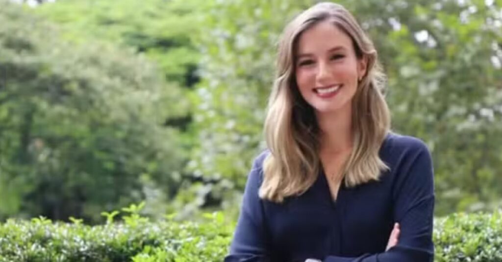Retrato de Luana Lara Lopes, bilionária mais jovem do mundo, sorrindo em área externa com vegetação ao fundo.