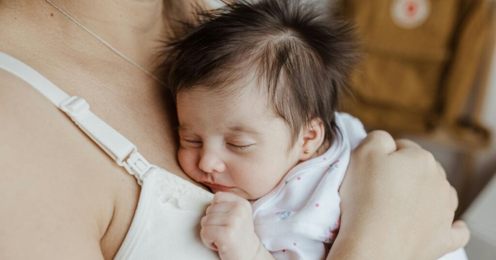 Mãe segura bebê no peito em cenário doméstico, simbolizando cuidado materno após Brasil elimina transmissão do HIV.