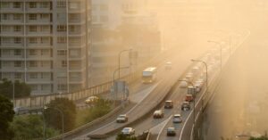 Calor urbano intenso em avenida com trânsito e prédios altos