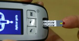 Pessoa verificando a glicemia com medidor digital, ação importante para quem segue alimentação para diabéticos.