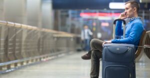 Homem aguarda no aeroporto enquanto verifica direitos do passageiro com voo cancelado