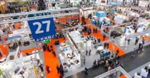 Vista aérea de estandes e visitantes em uma grande feira industrial, ilustrando o ambiente dinâmico da Feira FIEC.
