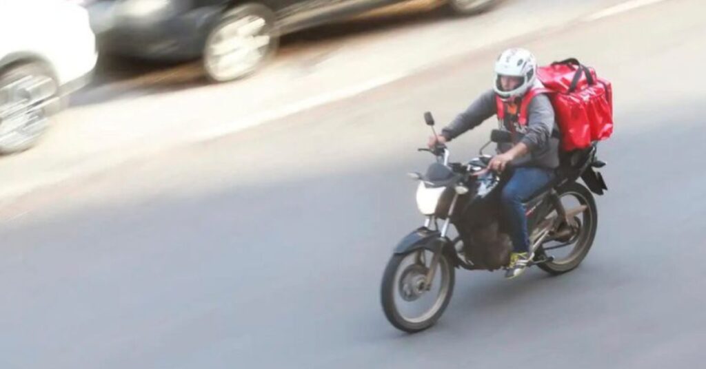 entregadores por aplicativo realizando entrega de moto em área urbana