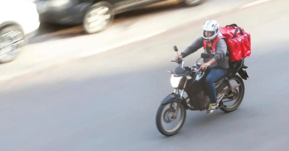 entregadores por aplicativo realizando entrega de moto em área urbana