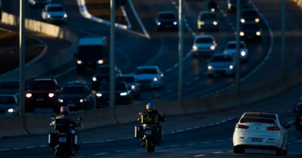 carros mais econômicos circulando em rodovia com tráfego urbano ao entardecer