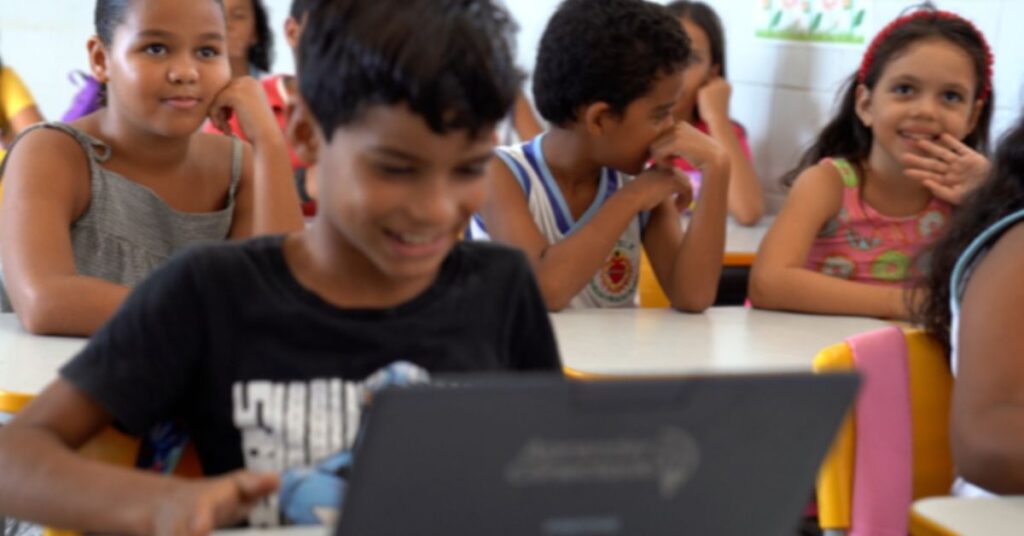 Alunos em sala de aula usando computador após investimento na educação pública
