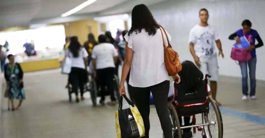 pessoa com deficiência sendo acompanhada em área de circulação com acessibilidade