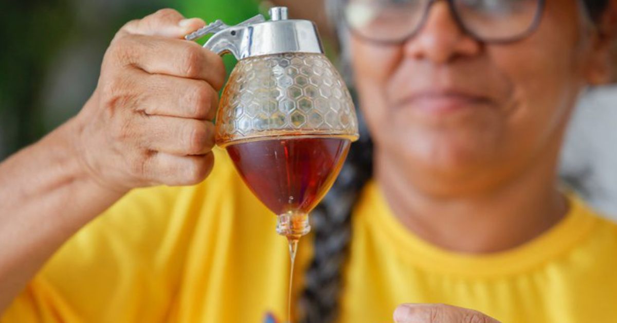 produção de mel artesanal com apicultora segurando recipiente com mel fresco