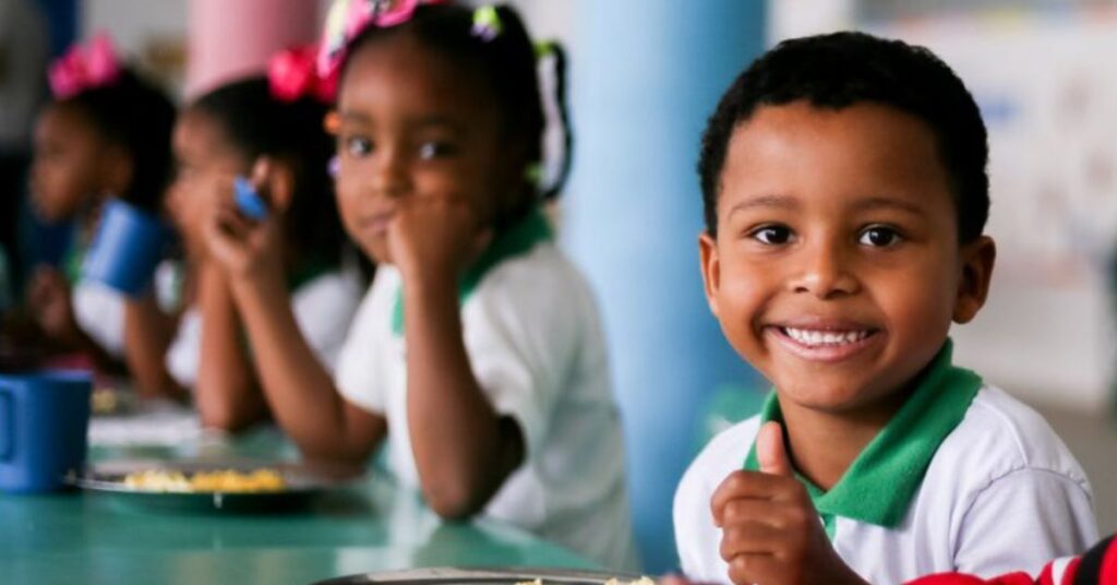Crianças em escola pública durante refeição, refletindo a queda da fome infantil no Brasil