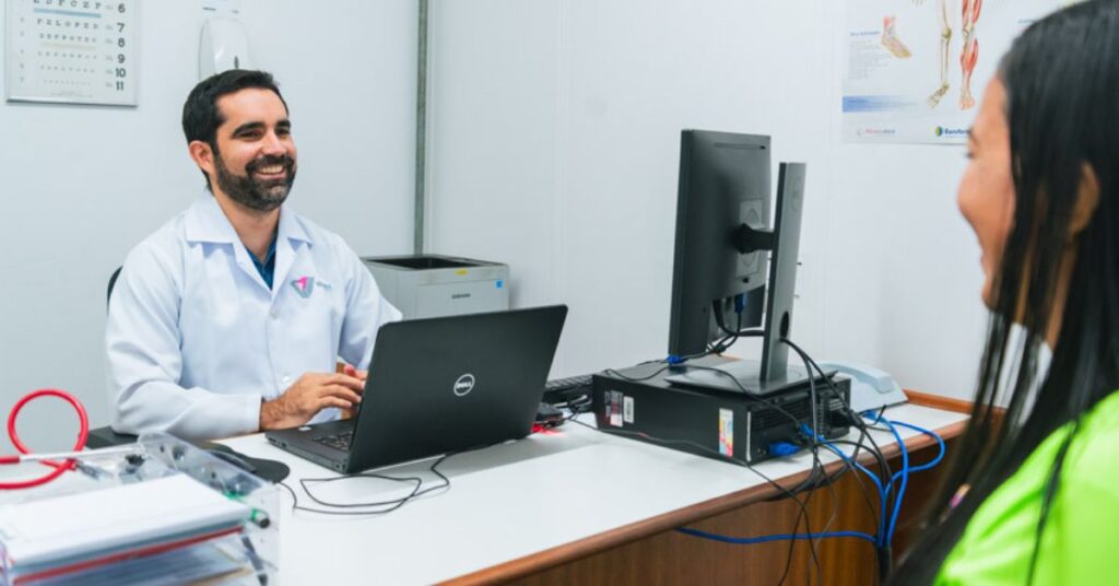 Profissional de saúde atende trabalhadora em consultório durante ação de saúde do trabalhador.