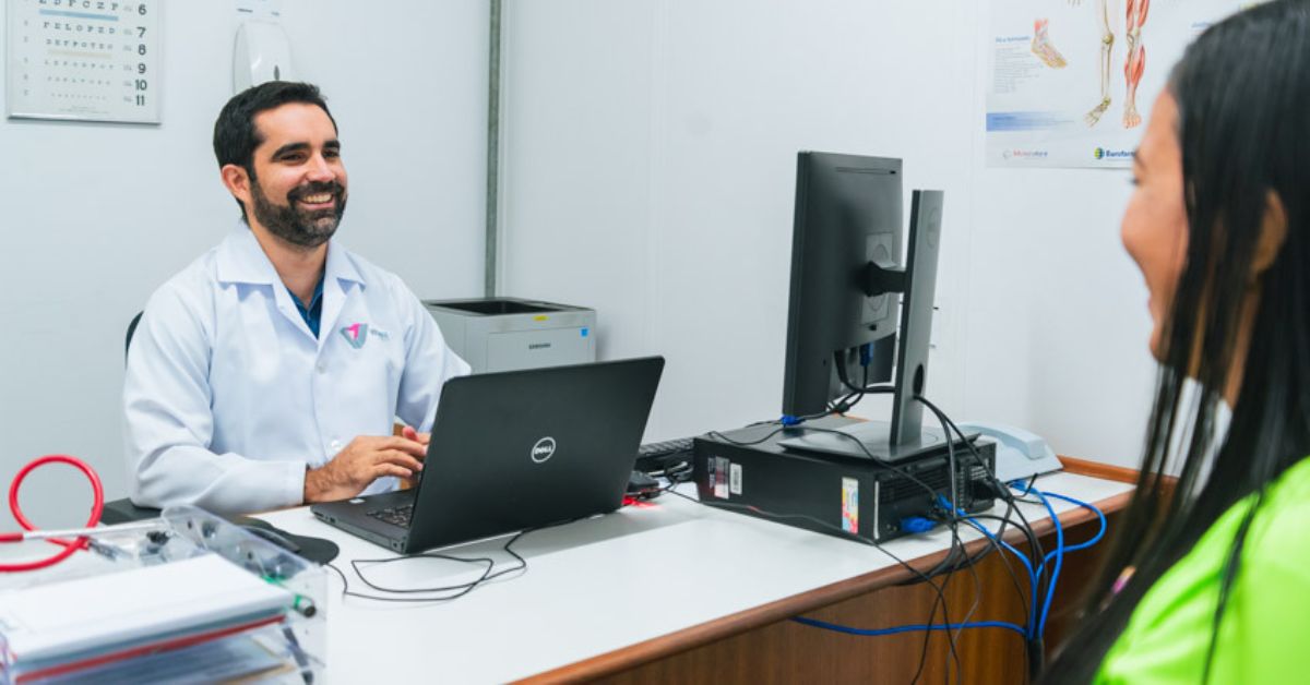 Profissional de saúde atende trabalhadora em consultório durante ação de saúde do trabalhador.