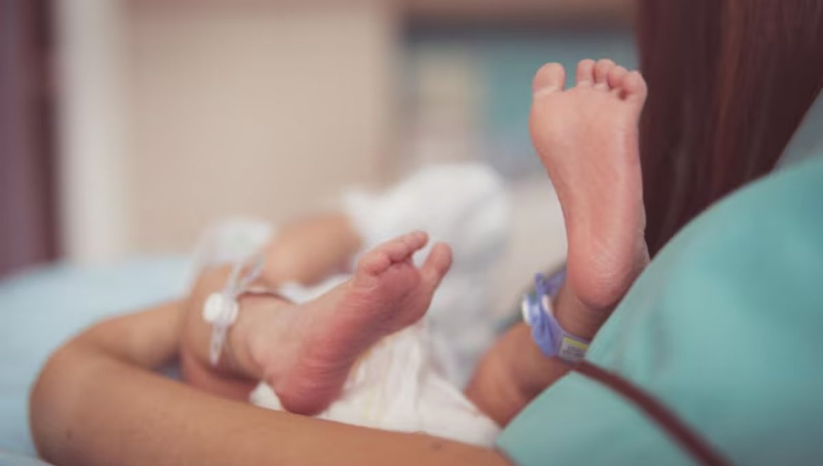 Recém-nascido em UTI neonatal sendo monitorado, com foco nos pés do bebê durante cuidados médicos