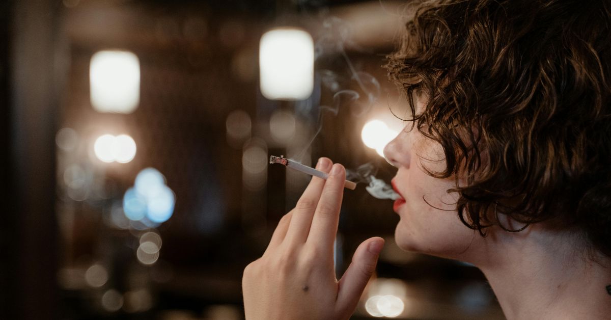 Jovem fumando cigarro em ambiente interno ilustra debate sobre proibição de cigarro no Reino Unido