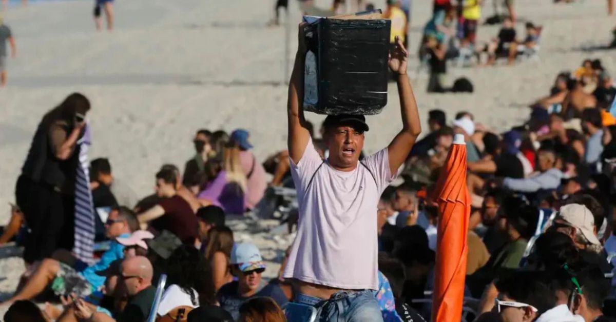 Trabalhador informal vende produtos em praia do Nordeste durante alta temporada do turismo