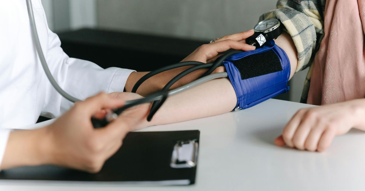 Profissional de saúde mede pressão arterial de paciente durante exame para diagnóstico precoce da hipertensão silenciosa