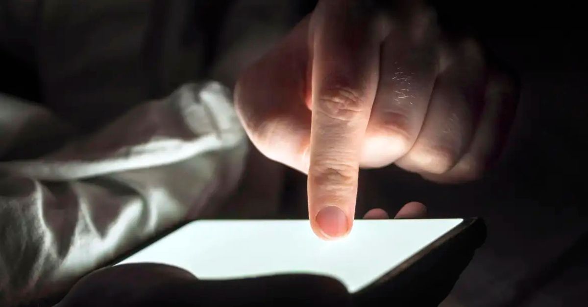 Pessoa usando celular no escuro representa avanço das apostas online e debate sobre proibição da publicidade de bets no Brasil