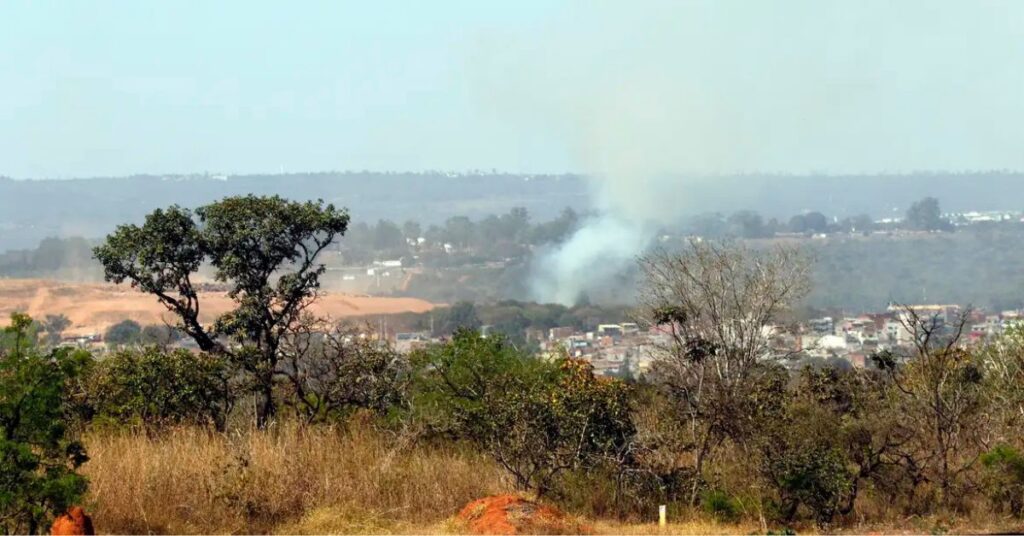 Área urbana com baixa cobertura vegetal e fumaça ao fundo em região afetada pelas ilhas de calor nas periferias brasileiras