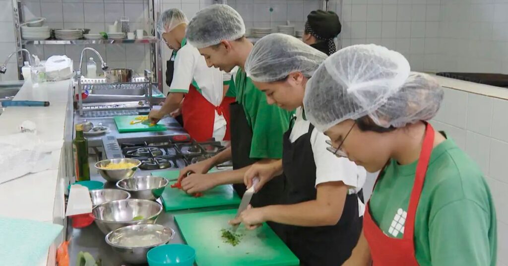 Alunos participam de aula prática de gastronomia durante formação profissional, iniciativa ligada à qualificação para o mercado de trabalho em meio à queda do desemprego no Brasil.