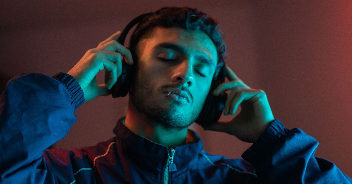 Homem usando fones de ouvido enquanto escuta músicas em streaming, tema relacionado ao detector de músicas com IA e identificação de faixas criadas por inteligência artificial.