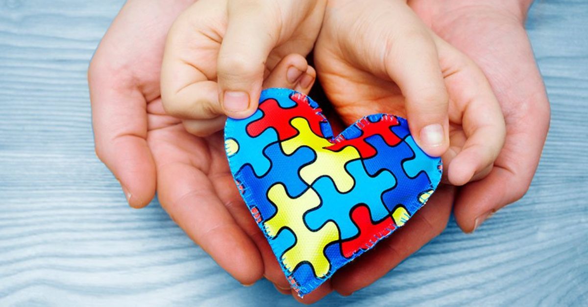 Dia do Orgulho Autista: mãos seguram coração colorido que simboliza inclusão, neurodiversidade e acolhimento de pessoas com TEA