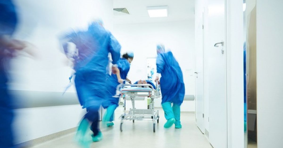 Equipe médica transporta paciente em hospital durante atendimento de emergência, ilustrando ações de resposta a emergências em saúde pública no Brasil.