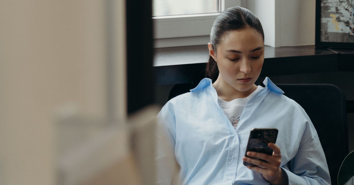 Mulher utiliza smartphone enquanto acessa ambiente digital em contexto de proteção digital feminina e combate à violência online.