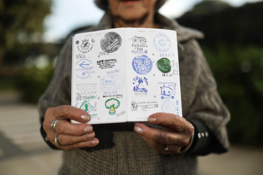 Marlene segura o passaporte do peregrino aberto, mostrando os carimbos obtidos durante o Caminho de Santiago.