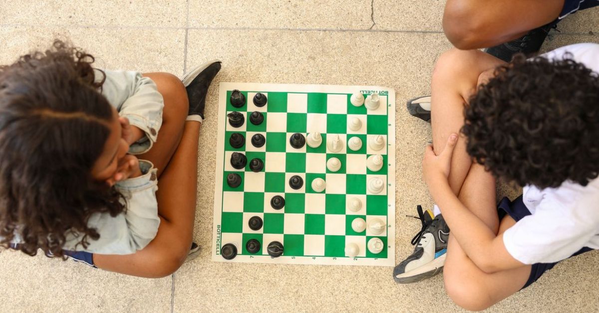 Crianças jogam xadrez enquanto pesquisa do IBGE mostra queda no número de crianças com celular devido à preocupação das famílias com segurança digital.