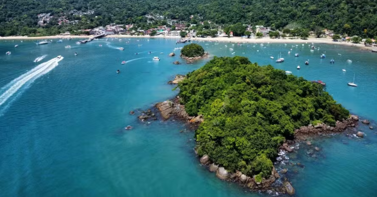 Vista aérea da Ilha Grande, no litoral sul do Rio de Janeiro, com águas azul-turquesa, áreas de Mata Atlântica, embarcações e faixa de praia ao fundo.