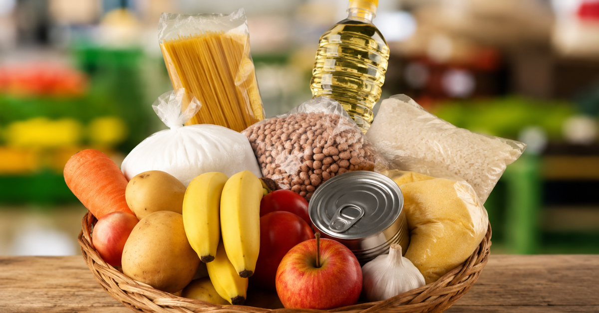 Cesta com alimentos básicos, como arroz, feijão, óleo, macarrão, frutas e legumes.