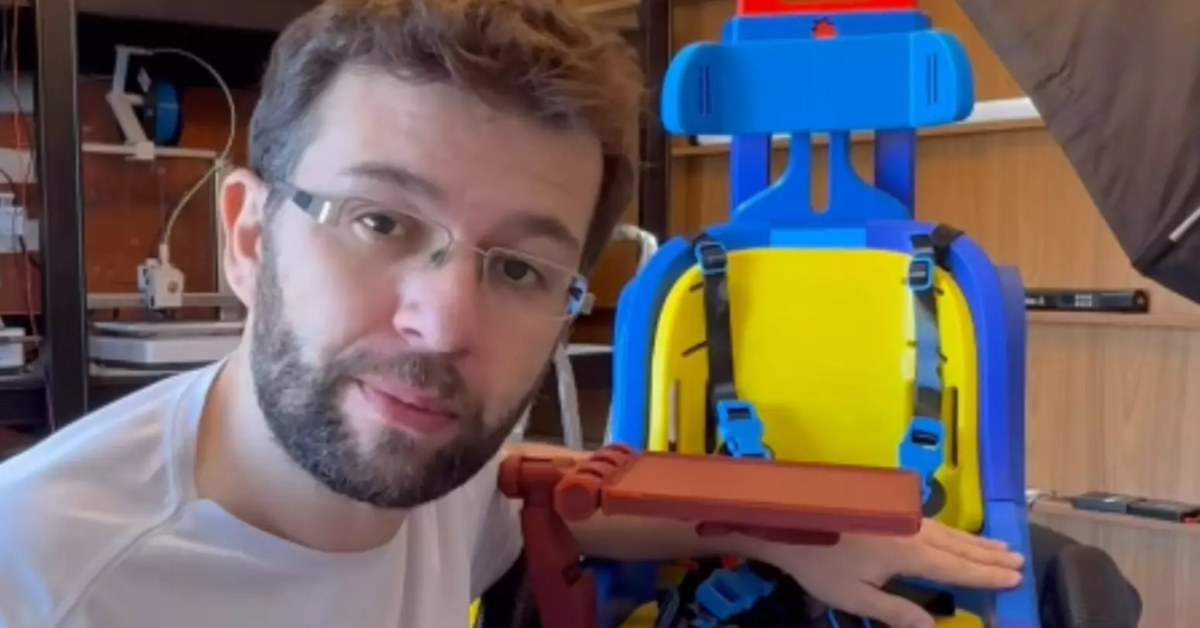 Ed Lima ao lado de cadeira de rodas infantil produzida com impressão 3D para doação.
