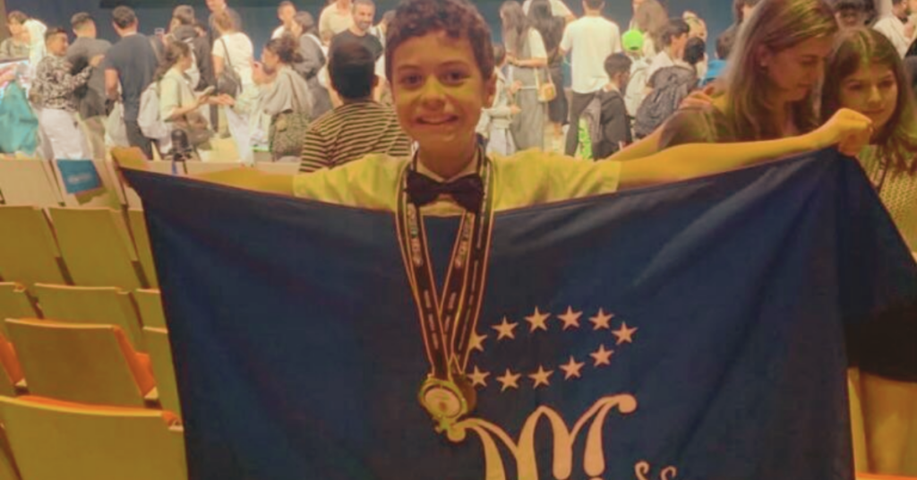 Estudante brasileiro exibe medalha de ouro conquistada na Olimpíada Internacional de Matemática após receber prêmio especial da competição.