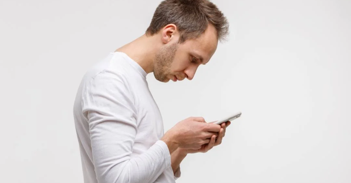Pessoa usando celular com a tela próxima à altura dos olhos para evitar sobrecarga no pescoço.